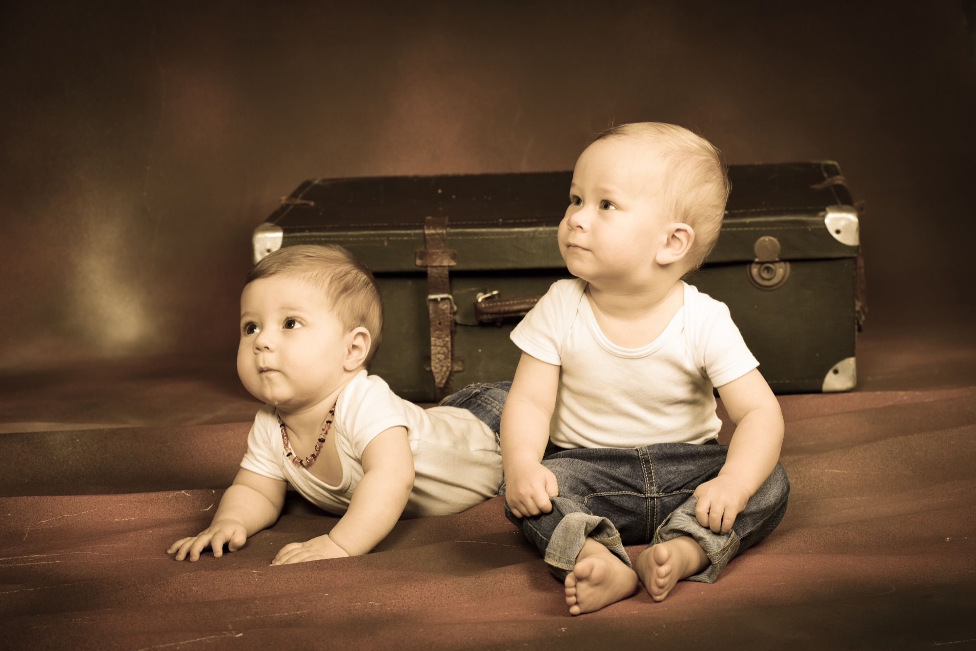 Zwei Babys vor einem alten Koffer